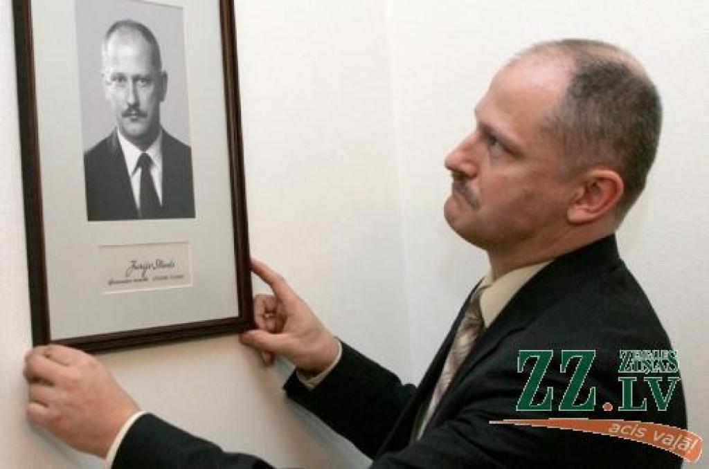 Atjaunotās Latvijas 16.ekonomikas ministrs Jurijs Strods piekar savu portretu ministru fotogalerijā.
Autors: LETA.