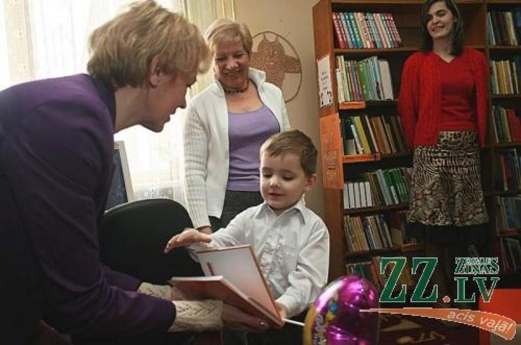 Mazais Ralfs no Miezītes bibliotēkas vadītājas Jolantas Treigutes saņem grāmatiņu «Burtumāja». Savulaik uz bibliotēku sācis nākt Ralfa tētis, kuram bija nepieciešams izmantot internetu. Ralfs pirmais iemēģinājis jauno bērnu stūrīti, un tagad atvedis sev līdzi māmiņu Ingu (sarkanajā jakā). Par jauno apmeklētāju priecājas arī bibliotekāre Alla Fialkovska.
Autors: Agris Samcovs.