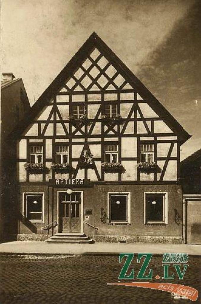 Tradicionāli vecajā un mūsdienu attēlā atainota aptuveni viena un tā pati vieta. Vecajā bildē redzam leģendāru Jelgavas namu, kas pirmskara pilsētā bija viens no vecākajiem un jau tolaik atzīts par senu un īpašu kultūras mantojuma pērli....