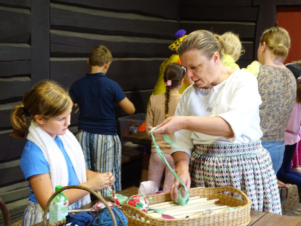 “Austras rakstu” vadītāja Aija Mālkalne kopā ar svētku apmeklētājiem gatavo senlatviešu rotājumus – ķistus.